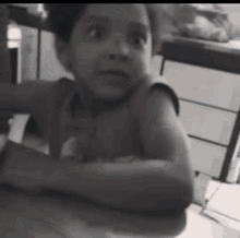 a young boy is sitting at a table in a black and white photo