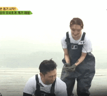 a man and a woman wearing overalls are playing a game with korean writing