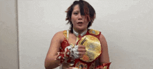 a woman in a wrestling outfit is holding a championship belt in her hands .