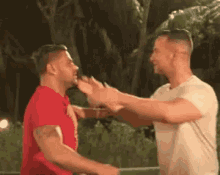 two men are standing next to each other and hugging .
