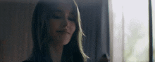 a woman is standing in front of a window in a dark room .