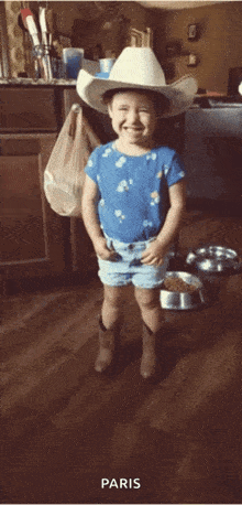 a little girl wearing a cowboy hat and shorts stands in front of a bowl of dog food