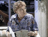 an elderly woman is sitting on a couch holding a piece of paper