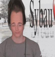 a man with a very large head is standing in front of a sybau sign