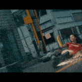 a woman wearing a red shirt that says super is laying on the street