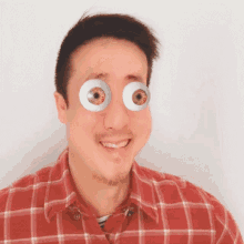 a man wearing a plaid shirt has a pair of fake eyes on his face