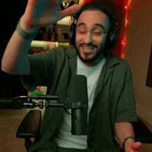 a man wearing headphones is sitting in front of a microphone and smiling