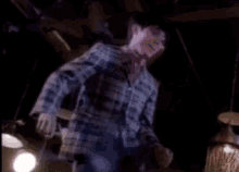 a man in a plaid shirt is holding a lantern in his hand .