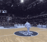 a man stands on a basketball court in front of a sign that says london