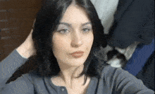 a woman with black hair and blue eyes is taking a selfie with her hand in her hair .