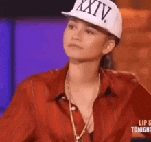 a woman wearing a hat and a red shirt is sitting on a stage .
