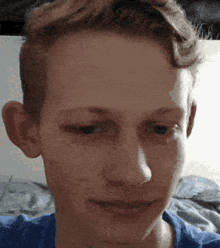 a young man in a blue shirt looks at the camera