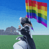 a person is holding a rainbow flag in a field