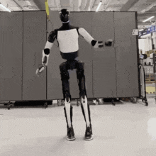 a black and white robot is standing in front of a wall that has the number 6 on it