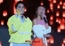 a man and a woman singing into microphones on a stage with #mayward written below them