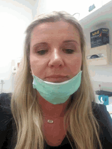 a woman wearing a surgical mask with a box of advil gloves behind her
