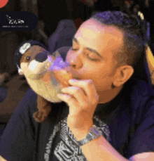 a man kissing a stuffed animal with a purple bottle in his mouth