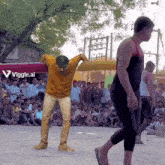 a man in a yellow shirt is dancing in front of a sign that says vigle.ai