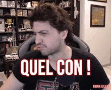 a man sitting in front of a microphone with the words quel con