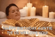 a woman is laying in a bathtub covered in waffles with candles in the background .