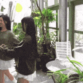 a woman in a green sweater is standing next to another woman in a white skirt