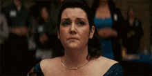 a woman in a blue dress is making a sad face while sitting in front of a crowd .