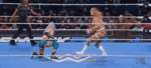 two women are wrestling in a ring with a referee standing behind them