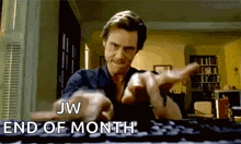 a man is typing on a keyboard and pointing at the camera with the words jw end of month .