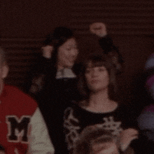 a group of people are sitting in a room and one of them is raising her fist in the air .