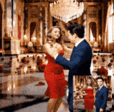 a man in a suit and a woman in a red dress are dancing