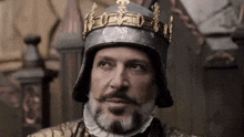 a man with a beard and a crown on his head is wearing a helmet .