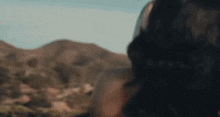 a woman is standing in front of a mountain and looking at the mountains .