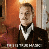 a man with a mustache is wearing a suit and tie and says this is true magic .