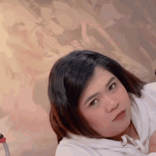 a woman in a white sweatshirt is looking at the camera