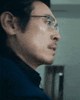 a man wearing glasses and a blue shirt looks to the side