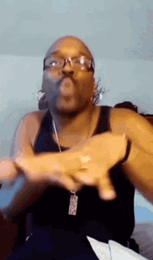 a man wearing glasses and a black tank top is making a face
