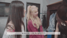 a girl in a pink plaid shirt talks to another girl in a room