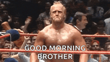 a shirtless wrestler is standing in a wrestling ring with a crowd behind him and says `` good morning brother '' .