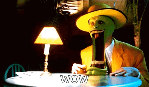 a man with a mask on his face is sitting at a table with the word wow on it