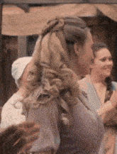 a woman with long blonde hair is wearing a purple dress and standing in a crowd of people .