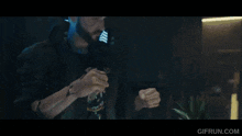 a man with a beard is wearing a futuristic mask and holding a sword in a dark room .