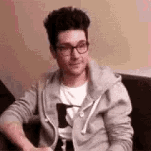 a man wearing glasses is sitting on a couch .