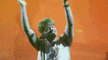 a man singing into a microphone with his arms up in the air