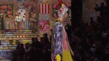 a model walks down the runway at a fashion show with a crowd watching