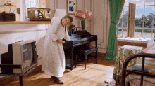 a woman standing next to a piano in a room