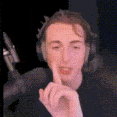a man wearing headphones is making a gesture with his finger to his lips .