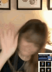 a woman is giving a high five while sitting in front of a wall with framed pictures on it .