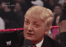 a woman in a suit and tie is talking into a microphone while wearing a fake trump wig .