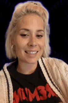 a woman wearing a black t-shirt that says mumba is smiling