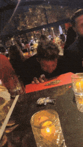 a man is sitting at a table with a candle in a glass
